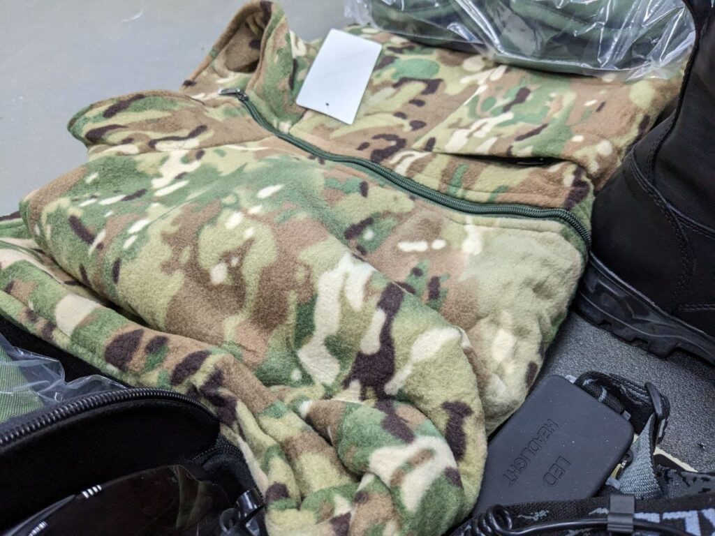 An image showing military clothing issued to new Wagner Group recruits at the Molkino training center in Krasnodar. The clothing consists of camouflage uniforms, boots, and protective gear.