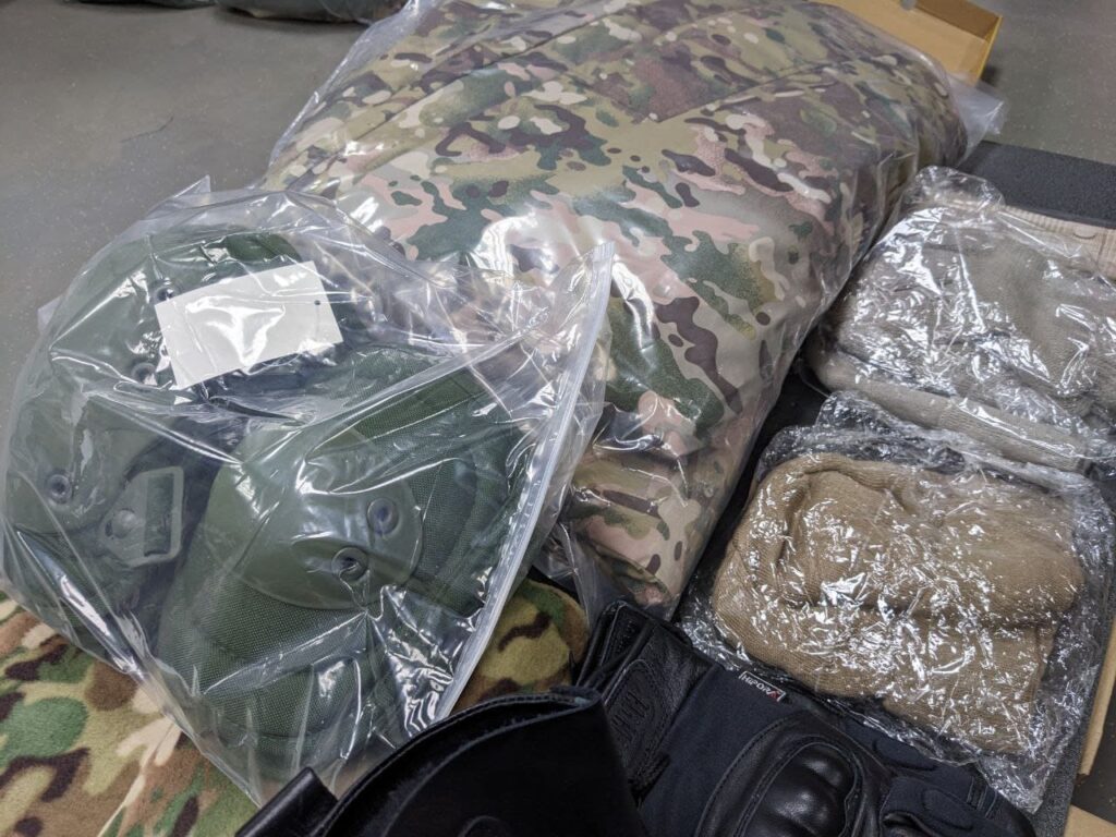 An image showing military clothing issued to new Wagner Group recruits at the Molkino training center in Krasnodar. The clothing consists of camouflage uniforms, boots, and protective gear.